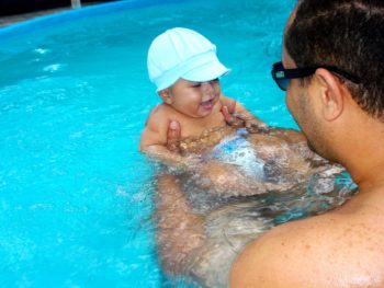 bébé nageur dans une piscine avec son papa en train d'apprendre à nager